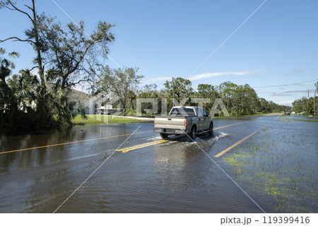 Hurricane flooded street with moving cars in surrounded with water Florida residential area. Consequences of natural disaster Hurricane flooded street with moving cars in surrounded with water Florida residential area. Consequences of natural disaster 119399416