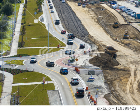 Industrial construction roadworks at roundabout intersection with moving cars in Venice, Florida. Development of urban circular transportation crossroads Industrial construction roadworks at roundabout intersection with moving cars in Venice, Florida. Development of urban circular transportation crossroads 119399422