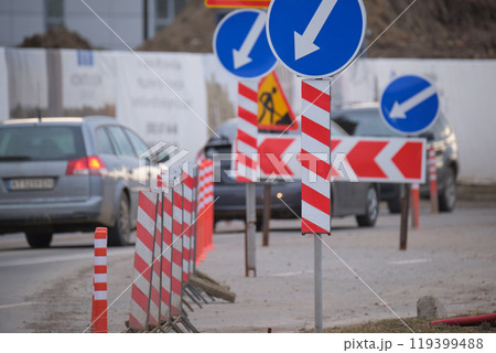 Roadworks warning traffic signs of construction work on city street and slowly moving cars 119399488