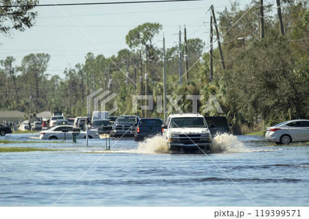 Flooded american street with moving vehicles surrounded with water in Florida residential area. Consequences of hurricane natural disaster 119399571