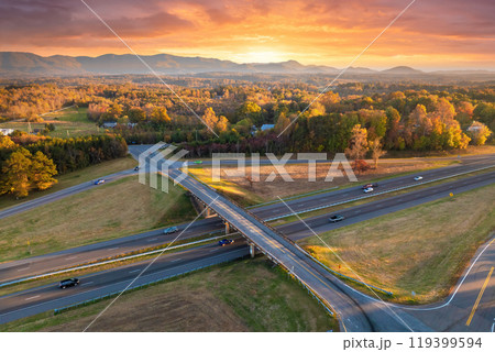 Freeway overpass junction with fast moving traffic cars and trucks in American rural area at sunset. Interstate transportation infrastructure in USA Freeway overpass junction with fast moving traffic cars and trucks in American rural area at sunset. Interstate transportation infrastructure in USA 119399594