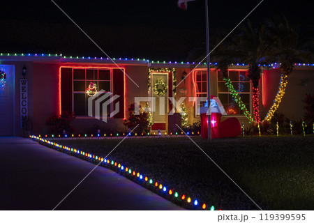 Front yard with brightly illuminated christmas decorations on driveway to house garage. Outside decor of florida family home for winter holidays Front yard with brightly illuminated christmas decorations on driveway to house garage. Outside decor of florida family home for winter holidays 119399595