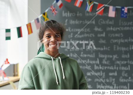 Portrait of Black female student smiling at camera while standing by blackboard in classroom, copy space Portrait of Black female student smiling at camera while standing by blackboard in classroom, copy space 119400230