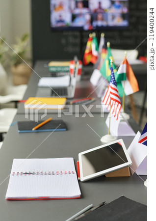 Vertical closeup of table with flags of different countries and digital tablet during lesson in school classroom, copy space Vertical closeup of table with flags of different countries and digital tablet during lesson in school classroom, copy space 119400244