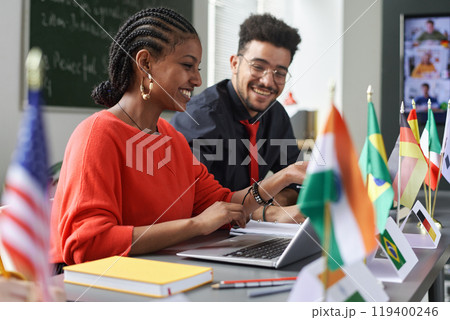 Two young students man and woman working on project together in multicultural school classroom, copy space Two young students man and woman working on project together in multicultural school classroom, copy space 119400246