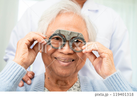 Optometrist checking Asian elderly woman ophthalmic vision eye test and using optical trial frame. 119401318