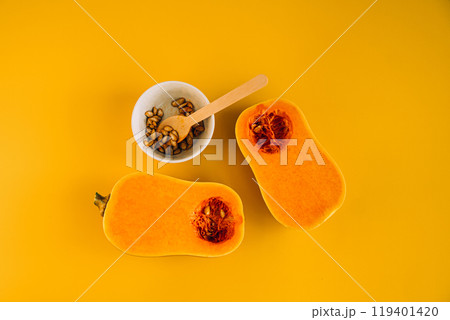Butternut squash halves on vibrant yellow background, highlighting pumpkin seeds and their health benefits Butternut squash halves on vibrant yellow background, highlighting pumpkin seeds and their health benefits 119401420