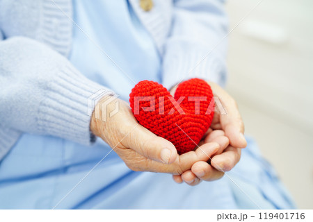 Asian elder senior woman patient holding red heart in hospital. 119401716