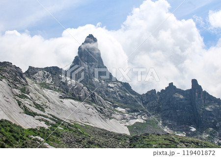 High Rocky Mountain peak against large white cloud, mountain landscape 119401872