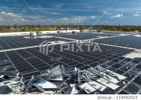 Destroyed by hurricane winds broken down photovoltaic solar panels mounted on industrial building roof for producing green ecological electricity. Consequences of natural disaster in Florida 119402023