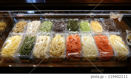 Colorful Variety of Fresh Pasta Noodles Displayed in Plastic Packaging at Market 119402211