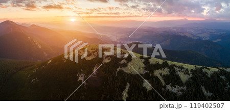 Aerial view of amazing scenery with foggy dark mountain peak covered with forest pine trees at autumn sunrise. Beautiful wild woodland with shining rays of light at dawn 119402507