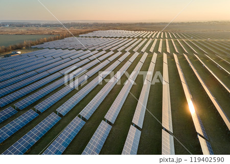 Aerial view of large sustainable electrical power plant with rows of solar photovoltaic panels for producing clean electric energy in evening. Concept of renewable electricity with zero emission Aerial view of large sustainable electrical power plant with rows of solar photovoltaic panels for producing clean electric energy in evening. Concept of renewable electricity with zero emission 119402590