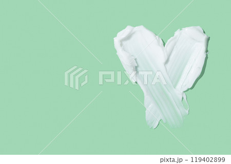 Beauty skincare cream texture swipe swatch in heart shaped. White beauty cream smear smudge isolated on green background 119402899