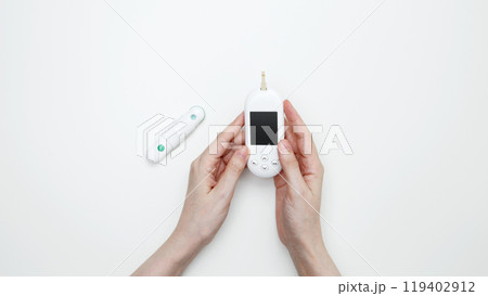 Female hands holding glucometer for measuring blood glucose levels, lancet. Concept of worldwide diabetes awareness Female hands holding glucometer for measuring blood glucose levels, lancet. Concept of worldwide diabetes awareness 119402912