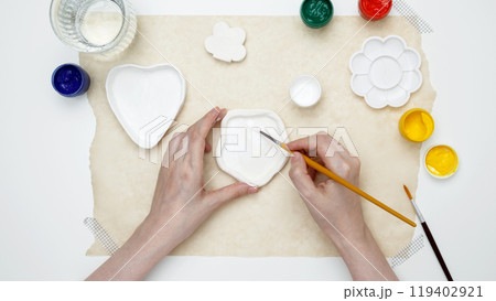 A woman paints clay products. Hobby clay modeling A woman paints clay products. Hobby clay modeling 119402921