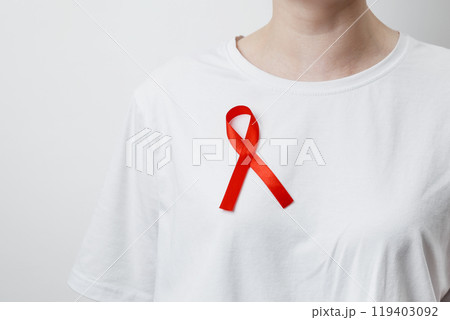 Woman wears red AIDS awareness ribbon. World AIDS Day 119403092