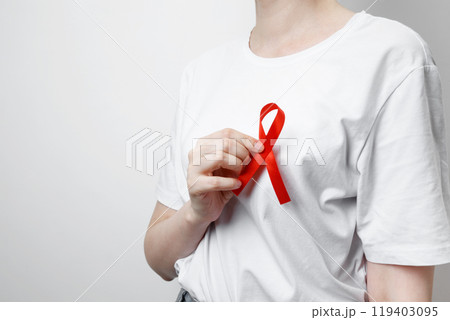 Woman holding red AIDS awareness ribbon. World AIDS Day Woman holding red AIDS awareness ribbon. World AIDS Day 119403095