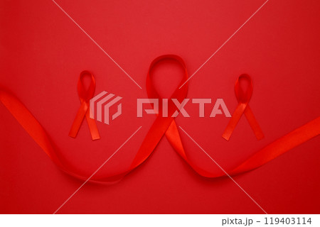 Red ribbons with awareness about AIDS on a red background. World AIDS Day 119403114