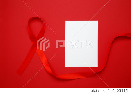 Red ribbon with awareness about AIDS on a red background and paper for mock up. World AIDS Day 119403115