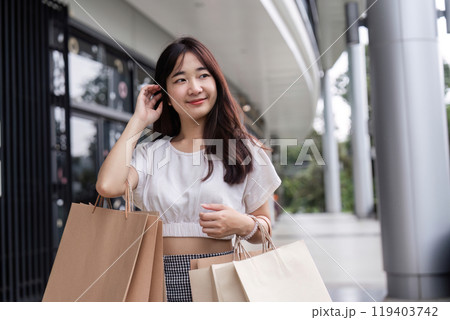 Young Woman Shopping with Paper Bags at a Modern Department Store on a Sunny Day 119403742