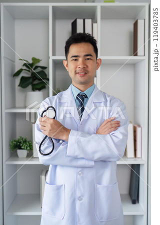 Confident Male Doctor in White Coat with Stethoscope Standing in Modern Medical Office Environment 119403785
