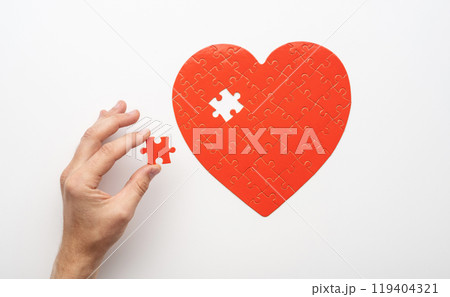 Hand holding piece near unfinished puzzle 119404321