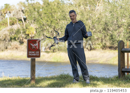 Operator is disappointed because he can not fly his quadcopter in national park no drone area. Man is unable to use his UAV near restriction notice sign 119405453