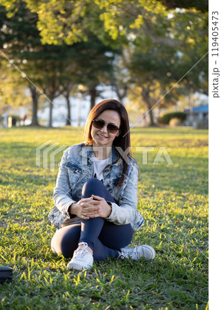 Happy stylish woman resting outdoors in city public park. Wellbeing and healthy lifestyle concept 119405473