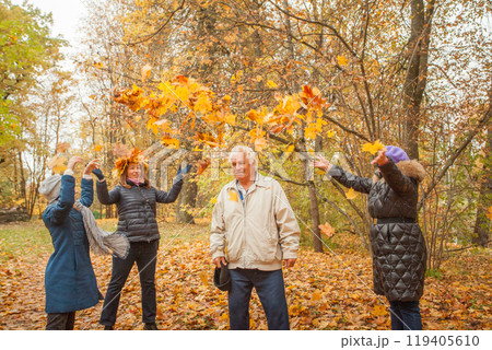 Senior grandma, mature muther and little child girl joyfully throwing autumn leaves at grandfather. Senior grandma, mature muther and little child girl joyfully throwing autumn leaves at grandfather. 119405610