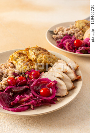 A wholesome plate featuring green buckwheat, chicken breast and zucchini pancakes paired with fermented vegetables 119405729