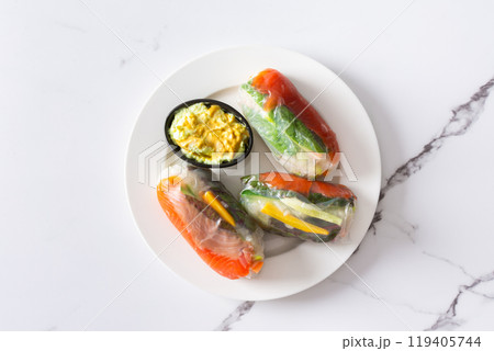 Enjoy Vietnamese spring rolls with rice paper, fresh lettuce, salmon, carrots, cucumber, and fish sauce, blending Asian and Thai cuisine for a delicious 119405744