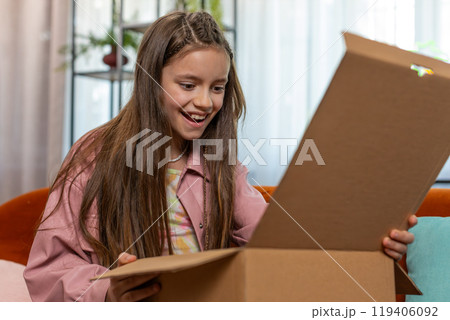 Happy amazed child kid girl unpacking delivery parcel opening cardboard box receiving purchase gift 119406092