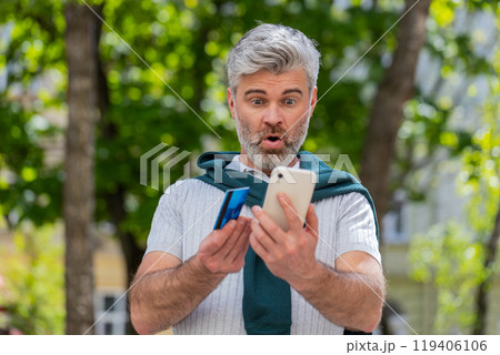 Shocked man trying to pay online shopping with smartphone blocked credit card lack of money balance Shocked man trying to pay online shopping with smartphone blocked credit card lack of money balance 119406106