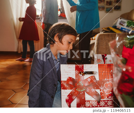 Little boy looking at presents near Christmas tree Little boy looking at presents near Christmas tree 119406515