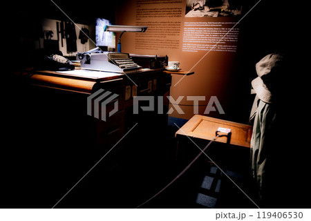 Vintage writing desk with typewriter and chair in a dimly lit museum exhibit highlighting early 20th-century literary history 119406530