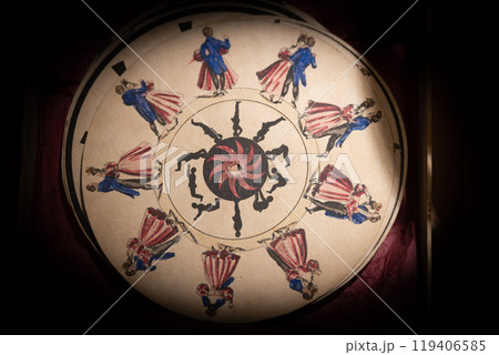 Intricate circular artwork featuring colorful figures dancing around a spiral design in a historical exhibit setting 119406585