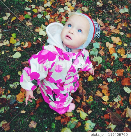 Little girl with blue eyes among colorful fallen leaves 119406760