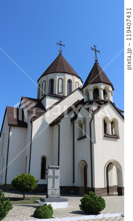 armenian apostolic church made of white stone with dark brown roof and landscape design of the territory, vertical photo, religious orthodox architecture in armenian style armenian apostolic church made of white stone with dark brown roof and landscape design of the territory, vertical photo, religious orthodox architecture in armenian style 119407431