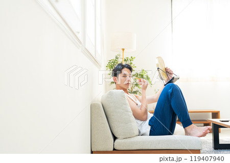 リビングでメイクをする若い男性 リビングでメイクをする若い男性 119407940
