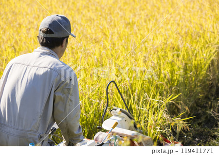 稲刈りイメージ　手押しの稲刈り機バインダーを使って稲を刈る男性 119411771