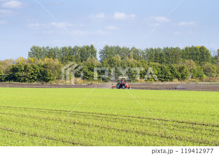 農地を耕す赤いトラクター　北海道帯広市 119412977