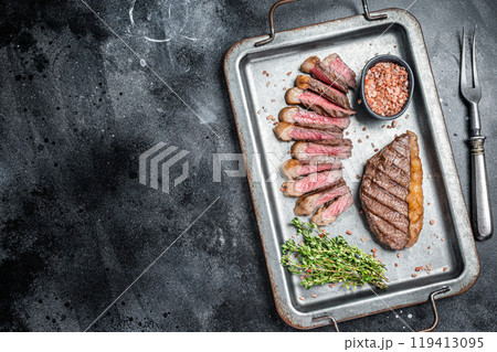 Fried and sliced Top sirloin steak, Grilled cup rump beef meat steak on a steel serving tray with spices. Black background. Top view. Copy space Fried and sliced Top sirloin steak, Grilled cup rump beef meat steak on a steel serving tray with spices. Black background. Top view. Copy space 119413095