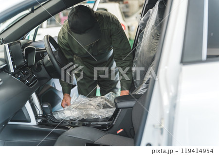 整備工場に入庫したお客様の車に養生カバー・シートカバーをする整備士の男性 119414954