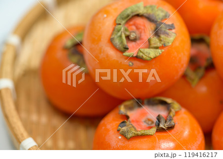 Delicious ripe persimmons in bowl on blurred background, closeup 119416217