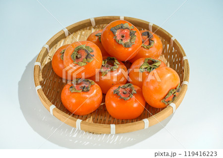 Delicious ripe persimmons in bowl on blurred background, closeup 119416223