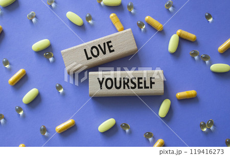 Love Yourself symbol. Concept words Love Yourself on wooden blocks. Beautiful purple background with pills. Mindfulness and Love Yourself concept. Copy space. 119416273