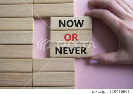Now or Never symbol. Concept words Now or Never on wooden blocks. Businessman hand. Beautiful pink background. Business and Now or Never concept. Copy space 119416661