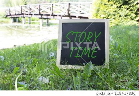 Story Time symbol. Concept word Story Time on black chalk background. Beautiful meadow background with bridge. Business and Story Time concept. Copy space 119417836