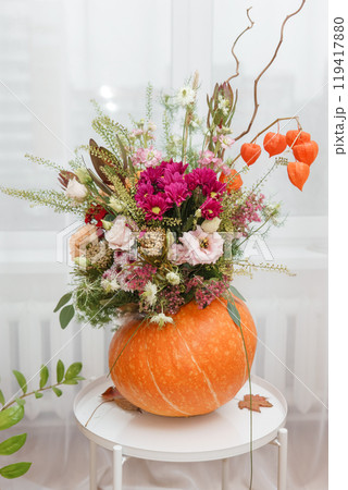 Flower arrangement in a pumpkin, autumn interior decor. Creating handmade autumn decor. 119417880